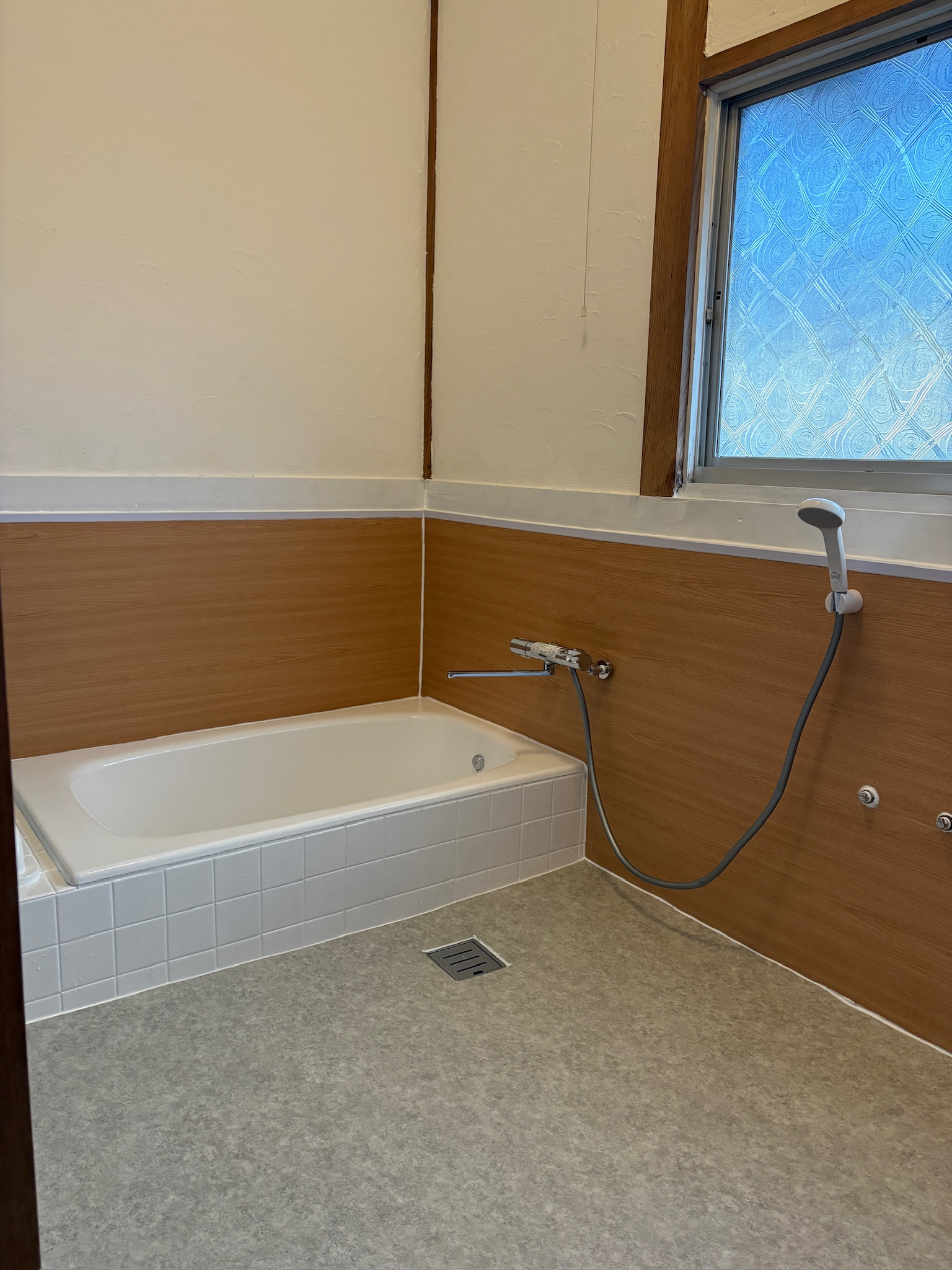 お風呂リノベAfter：木目調の壁と白い浴槽