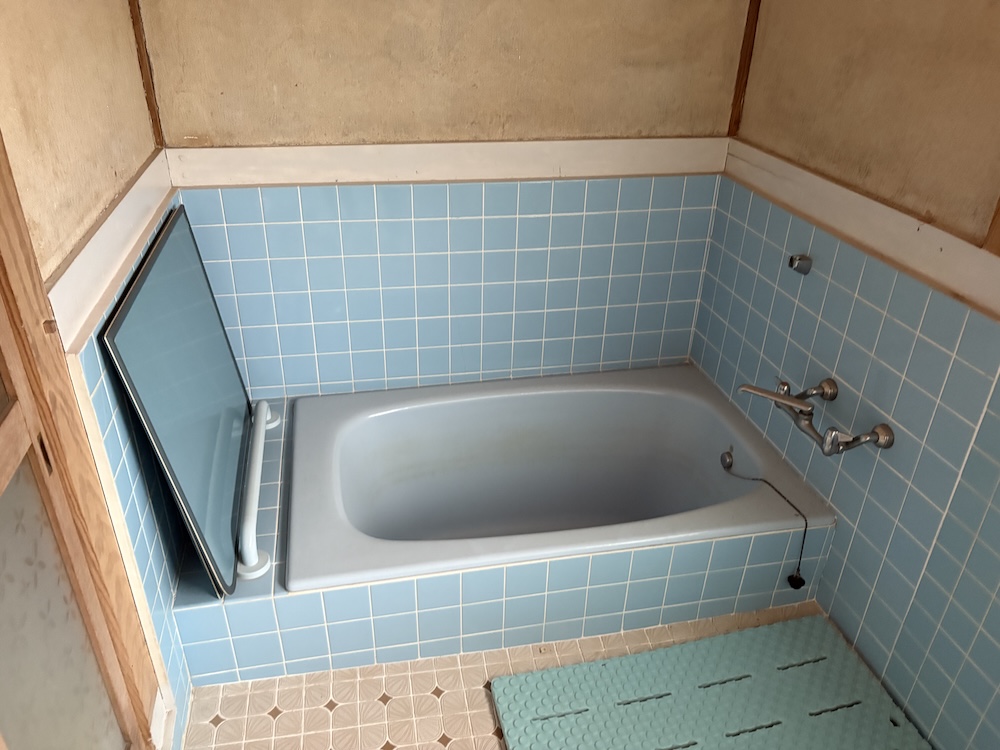 リノベ前の浴槽。古い水色タイルに囲まれている